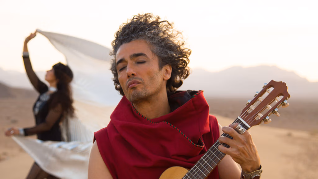 Om Shira playing acoustic guitar in the desert